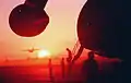 A C-130 Hercules aircraft takes off in the distance as a section of a Military Airlift Command C-5B Galaxy aircraft, foreground, is silhouetted by the morning sun at Grootfontein Logistics Base.