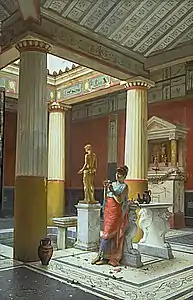 The figure is leaning against the cartibulum, the lararium is against the wall behind her, and the statue to her right is a small fountain cascading into a shallow trough and thence into the impluvium.