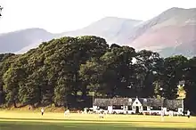 Cricket ground with wooded hills at the rear