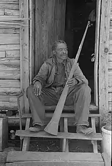 Elderly man born in slavery displays a horn formerly used to call slaves, Texas