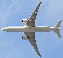 Aircraft in flight, underside view. The jet's two wings have one engine each. The rounded nose leads to a straight body section, which tapers at the tail section with its two rear fins.