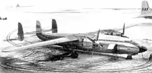 Photograph of two-engine turboprop aircraft with three vertical stabilisers parked on snow-covered ramp.