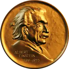 Obverse of a golden medal with the image of Albert Einstein facing right, the name Albert Einstein at the lower left and the dates 1835-1955 below the name.