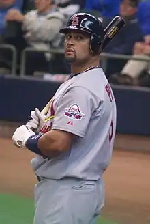 A man in a gray baseball uniform and navy blue batting helmet