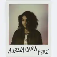 A polaroid of Alessia Cara. The artist's name and song title are written in black on the polaroid.
