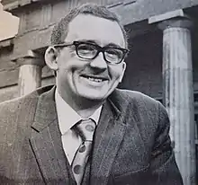 Allen Butterworth, smiling and wearing a suit, is stood outside of the Yorkshire Museum