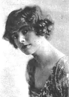 A young white woman with bobbed wavy hair, wearing a dress with a square neckline