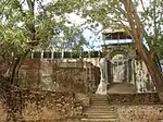 A picture of a fortified wall and gate between two trees.