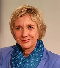 Amelie Fried wearing a purple blazer and blue patterned scarf, smiling at camera