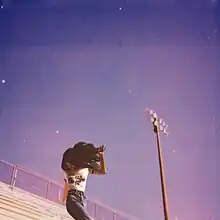 A young woman standing on football bleachers in front of a blue sky