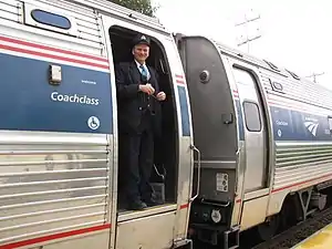 A uniformed conductor in a train doorway