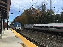 Pittsburgh-bound Amtrak Pennsylvanian passes Exton station while a New York City-bound Amtrak Keystone Service train stops at the station in November 2018