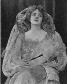 A young white woman, seated, wearing a gown and a large fur with a high collar.