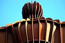 Vertical parallel ribs run from the head of the Angel of the North down the rest of its body.