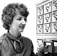 a white woman with short curly hair looking over a card catalog