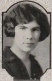 A young white woman with dark hair in a wavy bobbed style, wearing a dark collared blouse