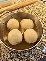 four dumplings in their dish, half-covered in a thin sauce.