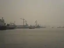 port quayside can be seen shrouded in hazy fog, obscuring cranes and piers