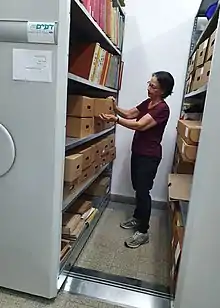 Archivist retrieves files from mobile storage rack at Kibbutz Lochamei Hagetaot