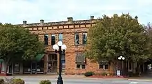 A two-story stone building on a downtown street.