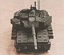 An AGS as seen from a high angle. The sides of the turret, track skirts and glacis plate are covered by thick boxes. The commander's station is armed with an M2 Browning .50 caliber machine gun.