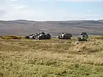 photo of armoured vehicles easy to see on bare hillside