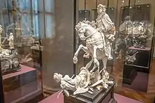A table-top sized statue in ivory of a mounted figure.  The horse is reared-backward, trampling a supine figure representing the "horrors of war."