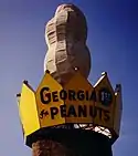A giant peanut surrounded by a yellow crown on which is written "Georgia First In Peanuts"