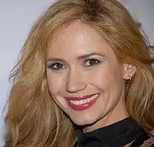 A woman with blond hair, wearing a black top.