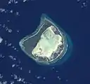 Astove Atoll, slightly oblique view from space.Note the wide land area (dark) surrounding the whitish lagoon