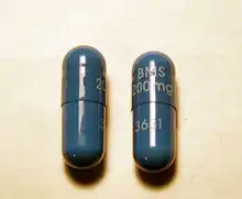 Two dark blue capsules with writing on them