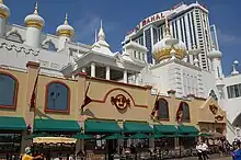 The facade of the Trump Taj Mahal, a casino in Atlantic City. It has motifs evocative of the Taj Mahal in India. A tall building with the resort's name stands in the background.