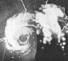 Black and white radar image of a hurricane. Rain is visible as white shapes. The cyclonic circulation of the rains is apparent, and the hurricane has a void of rain near its center, denoting an eye.