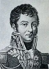 Black and white print shows a young man dressed in a high-collared, dark military coat trimmed with braid.