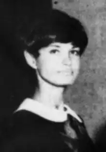 A young white woman with dark hair cut in a fringe, wearing a dark dress with a white peter-pan collar