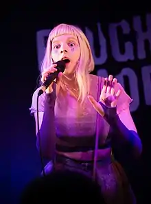 Aurora singing holding a microphone