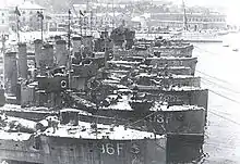 a black and white photograph of several ships at a dock