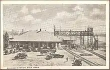 A postcard showing a railway station at a diamond crossing, with signal bridges over the tracks