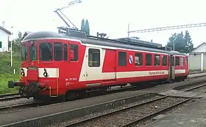 Red railcar with white stripe sitting at a station