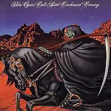 A skeleton in a black cloak carrying an scythe rides a black horse in a desert with a dark blue sky behind them.
