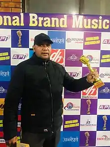 B. Pandey holding the best movie songwriter award at National Brand Music Award 2021