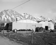 a white building with a rounded roof in utah valley. snow-capped mountains line the background