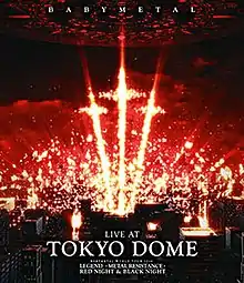A series of orange-yellow pyrotechnics stand out in a group of three, shaped like crosses, above a group of buildings with a dark, red sky; "BABYMETAL" appears at the top, and "LIVE AT", "TOKYO DOME", "BABYMETAL WORLD TOUR 2016", "LEGEND -METAL RESISTANCE-", and "RED NIGHT & BLACK NIGHT" appear at the bottom, all in white, all caps text.
