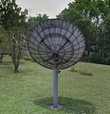 The back side of an old C-band satellite dish showing the pole, mount, motor, and structure of the dish.