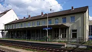 Side platform in front of wide two-story building with gabled roof