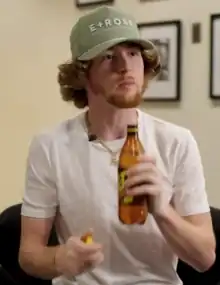 A waist-up view of singer Bailey Zimmerman, holding a bottle in his left hand.