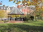 a bandstand in a park (temple gardens), with houses in the background