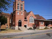 Old red-brick church building with arched entrance and stained-glass window