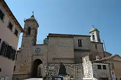 Brown-red brick church with a belltower, a clock over a tunnel, and a monument with white zig zags on the walls.