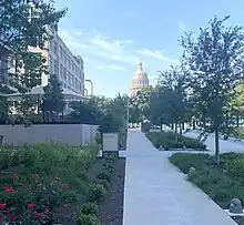 An image of the Barbara Jordan State of Texas office building on the left and the Texas State Capitol in the center taken at dusk.